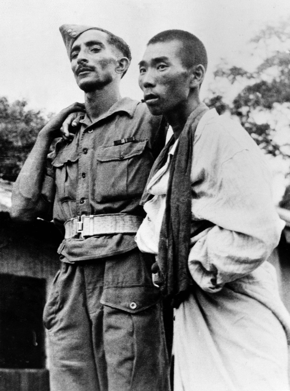 1945 के युद्ध में एक घायल जापानी कैदी की मदद करने वाली एक भारतीय सेना की दवा द्वारा अंग्रेजी फोटोग्राफर