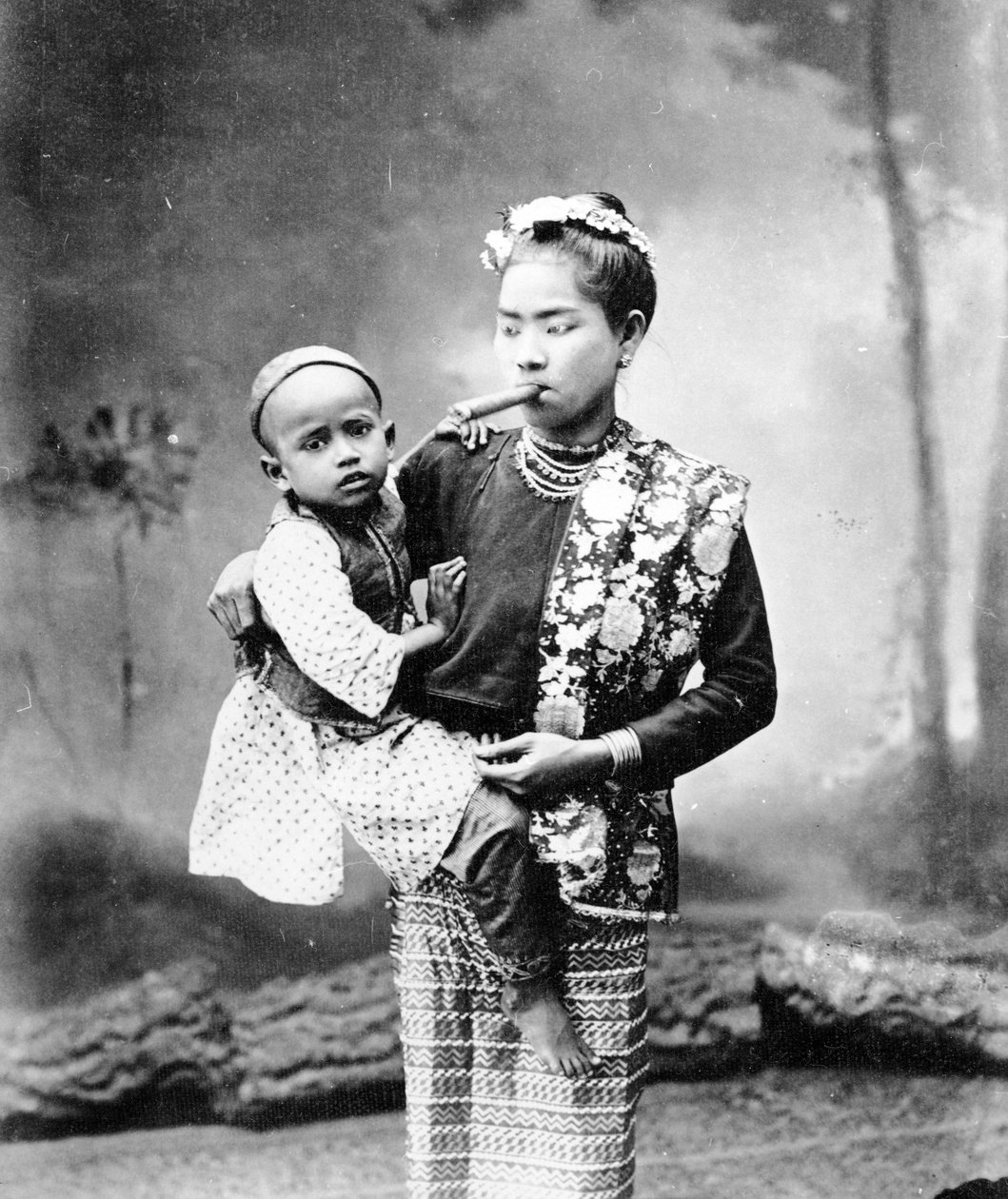 बर्मी वूमेन विद चाइल्ड एंड स्मोकिंग ए चेरूट, c.1870-90 द्वारा अंग्रेजी फोटोग्राफर