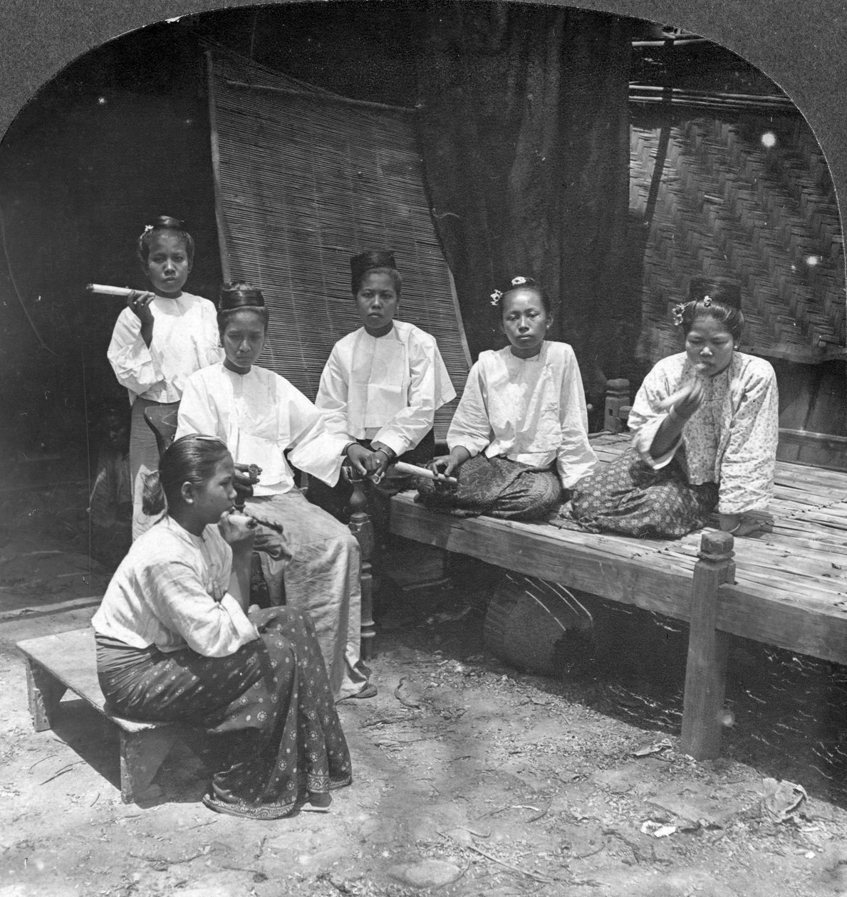 बर्मा की महिलाएं अपने घर के बाहर धूम्रपान करती हैं, मंडालय, बर्मा, 1908। द्वारा स्टीरियो यात्रा सह