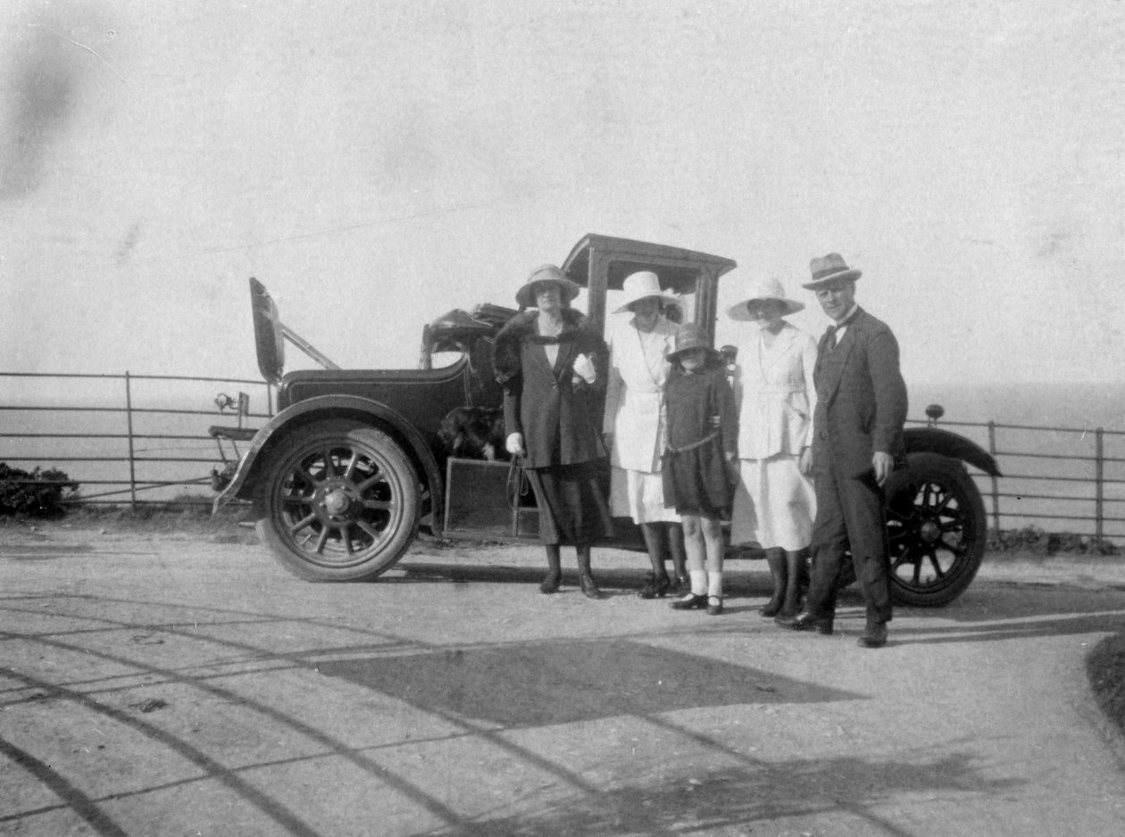 समुद्र के किनारे अपनी कार के सामने लोगों का एक समूह, c1920s द्वारा अज्ञात