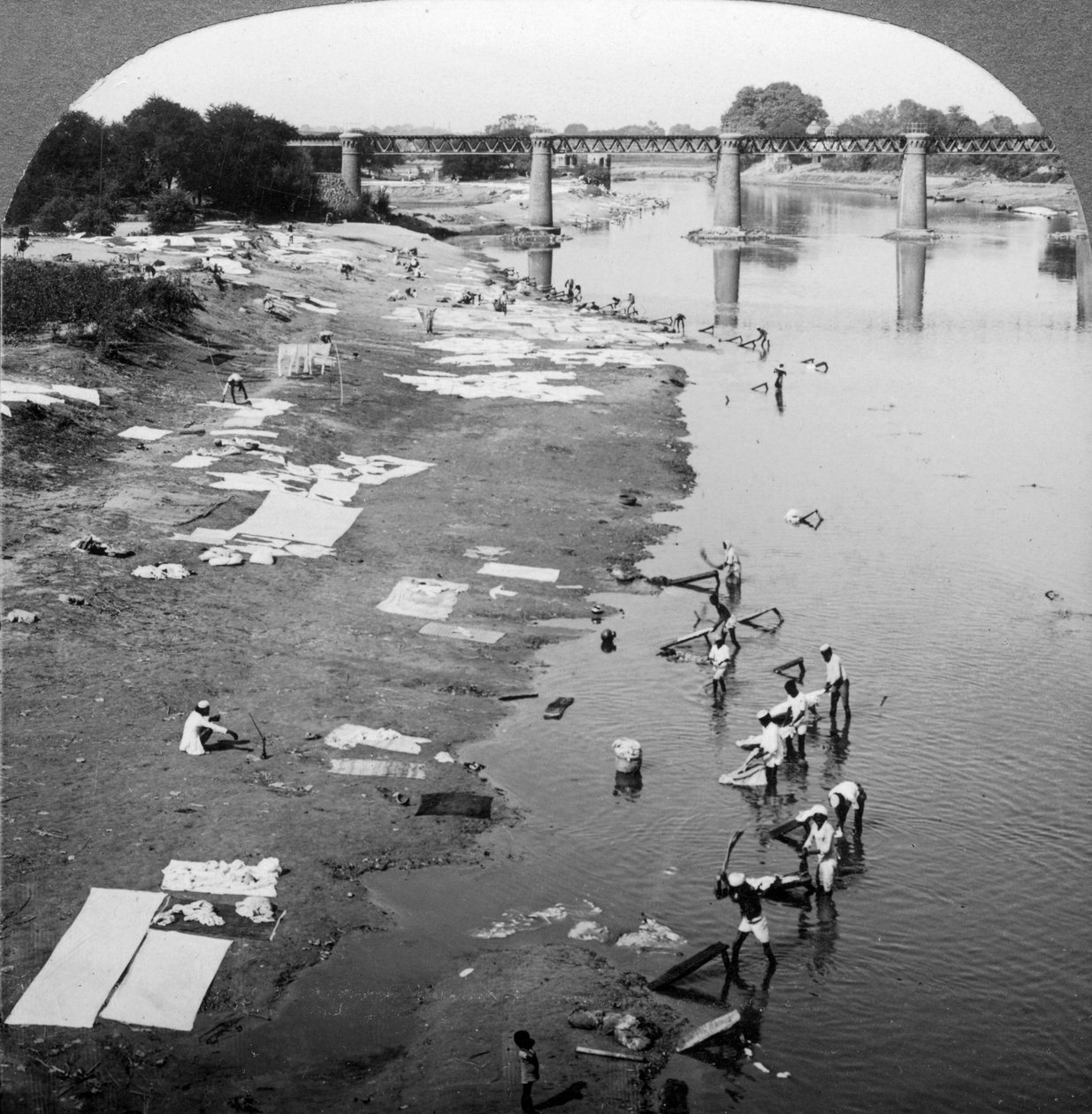 1900 के दशक में लखनऊ, भारत के पास स्थित गोमती नदी में कपड़े धोते डब्बू। द्वारा अंडरवुड और अंडरवुड