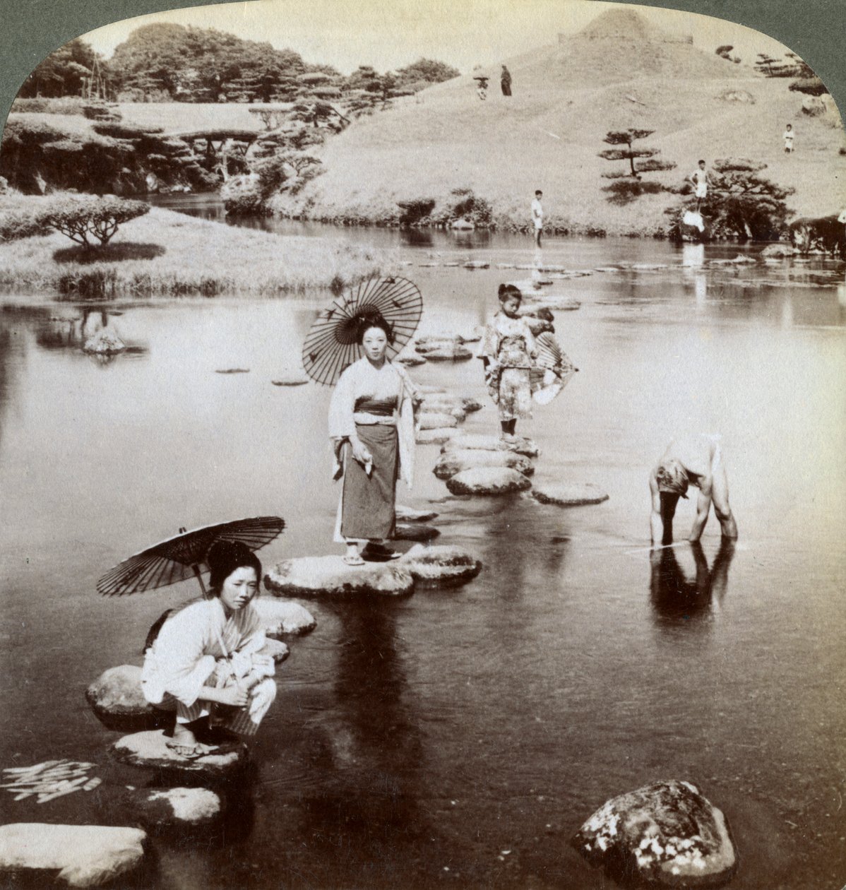 कदम-कदम पर झील पार करती महिलाएं, सुजेन-जी गार्डन, कुमामोटो, जापान, 1904। द्वारा अंडरवुड और अंडरवुड