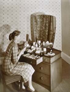 अपनी ड्रेसिंग टेबल पर महिला, c1955। द्वारा अंग्रेजी फोटोग्राफर
