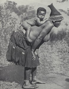 अपने बच्चे को पीठ पर उठाकर ले जाती महिला, दक्षिण अफ़्रीका (b/w photo)