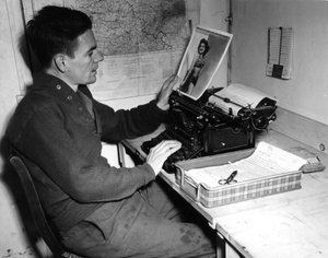 द्वितीय विश्व युद्ध (1939-1945) - द्वितीय विश्व युद्ध (WWII या WW2): मुत्ज़िग (अलसैस) फ्रांस 1 दिसंबर 1944: कॉरपोरल फ़्लैनर्टी क्रॉनिकलर ऑफ़ द बीचेड न्यूज़ (जीआई की न्यूज़ जर्नल) एक पिन-अप तस्वीर को देखता है जिसे वह प्रकाशित करता है अखबार का अगला अंक। द्वारा अज्ञात