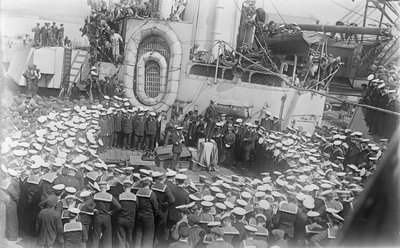 21 मई 1916 को डेवॉन, इंग्लैंड के डॉकयार्ड में HMAS ऑस्ट्रेलिया के डेक पर उन्हें संबोधित करते हुए ऑस्ट्रेलिया के प्रधान मंत्री माननीय विलियम मॉरिस (बिली) ह्यूजेस के चारों ओर भीड़ द्वारा ऑस्ट्रेलियाई फोटोग्राफर