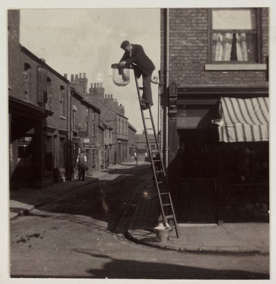 आदमी एक गैस स्ट्रीट लाइट की सफाई करता है, c 1905 द्वारा अज्ञात