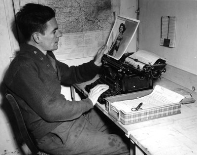 द्वितीय विश्व युद्ध (1939-1945) - द्वितीय विश्व युद्ध (WWII या WW2): मुत्ज़िग (अलसैस) फ्रांस 1 दिसंबर 1944: कॉरपोरल फ़्लैनर्टी क्रॉनिकलर ऑफ़ द बीचेड न्यूज़ (जीआई की न्यूज़ जर्नल) एक पिन-अप तस्वीर को देखता है जिसे वह प्रकाशित करता है अखबार का अगला अंक। द्वारा अज्ञात