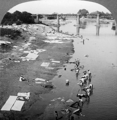 1900 के दशक में लखनऊ, भारत के पास स्थित गोमती नदी में कपड़े धोते डब्बू। द्वारा अंडरवुड और अंडरवुड